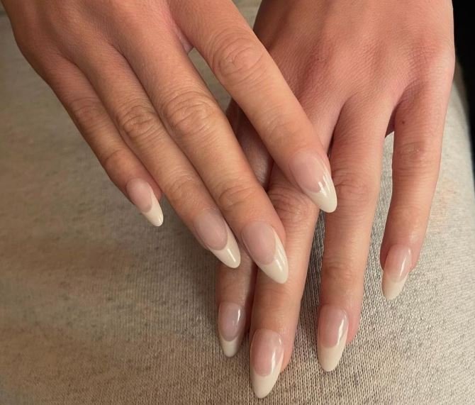 Long Almond Shape American Manicure - Natural clean, and polished American manicure nails featuring off-white, cream, or soft ivory shade tips, sheer nude, light pink, or milky translucent base and elongated almond giving a slender appearance.